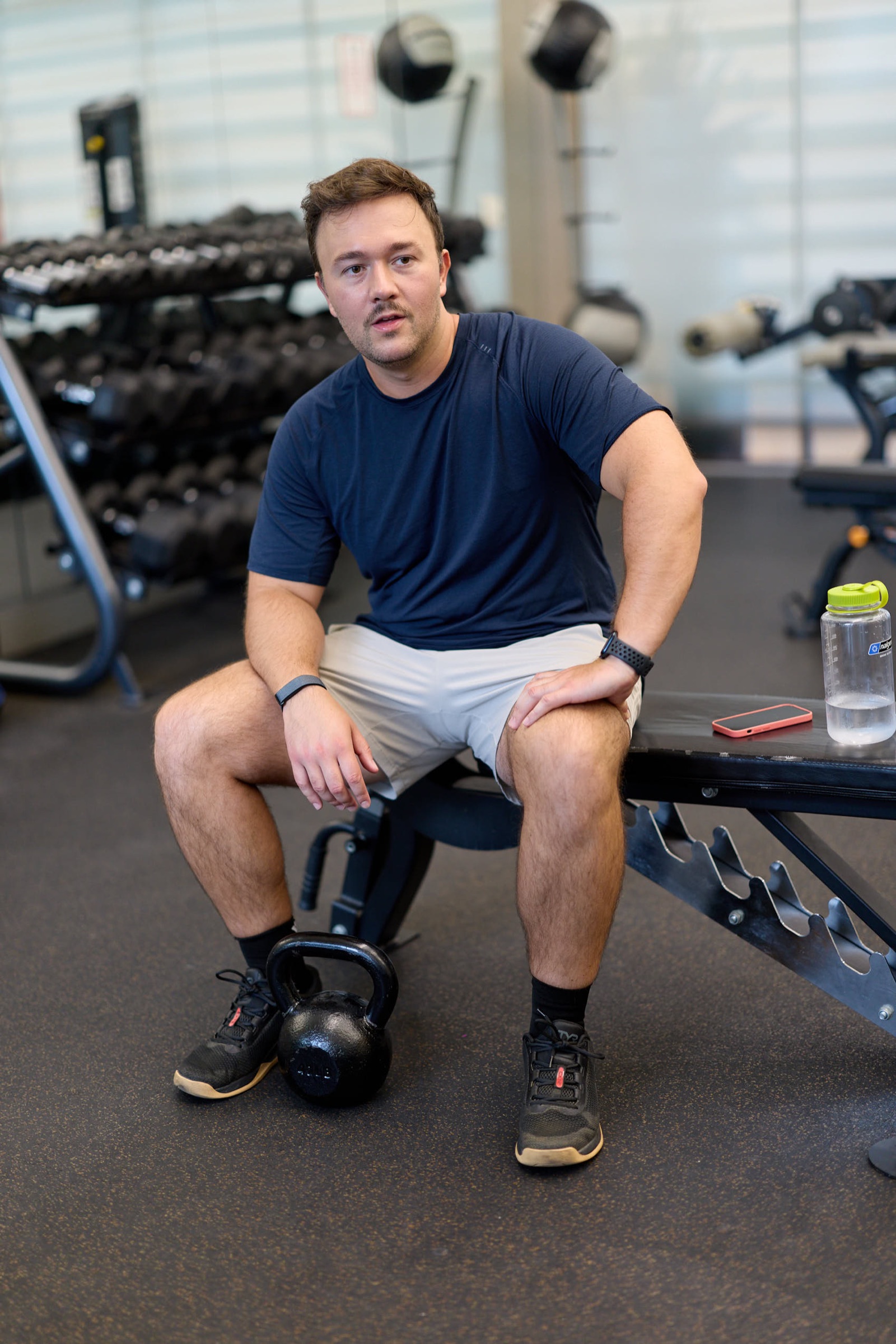 Man in workout clothes resting on a gym bench during a dating profile photo session