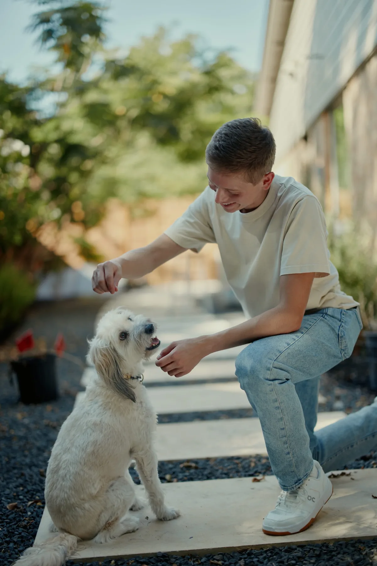 Man crouching to give a treat to a fluffy white dog, a candid dating profile photo