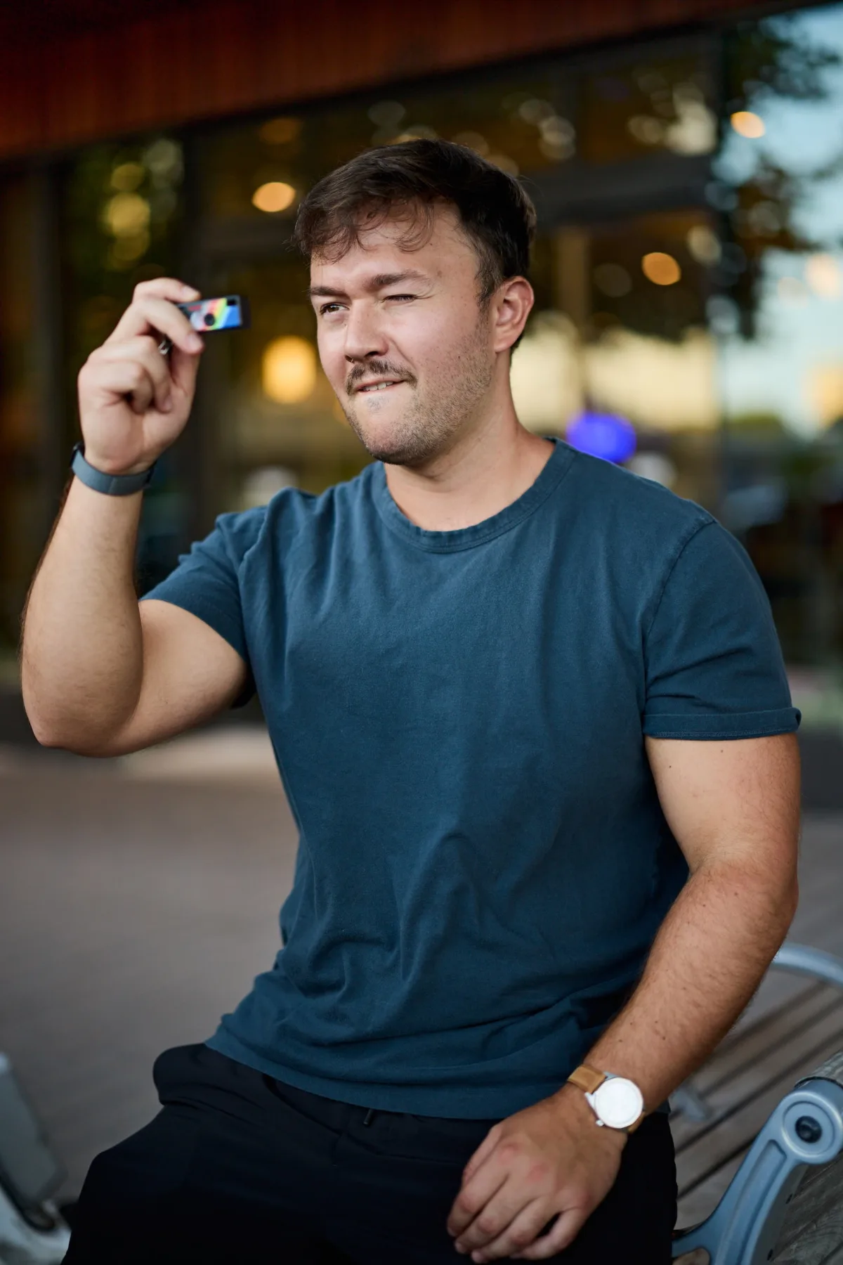Man winking while holding up a small camera, a playful dating profile photo