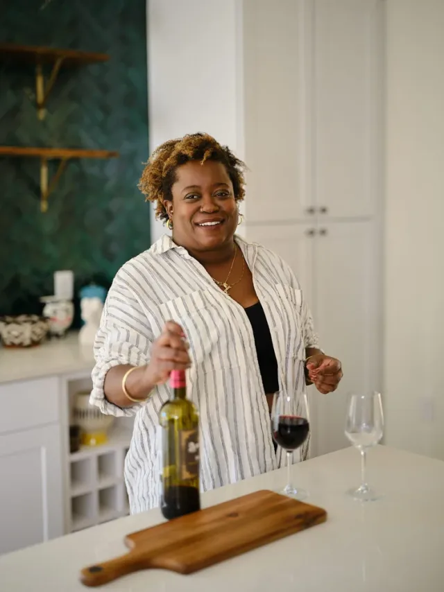 Woman laughing while opening red wine in a kitchen, a lifestyle shot from an Austin dating profile photography session