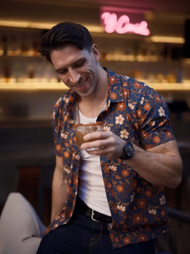 Man laughing at a cocktail bar holding a whiskey drink, an Austin online dating photography lifestyle shot