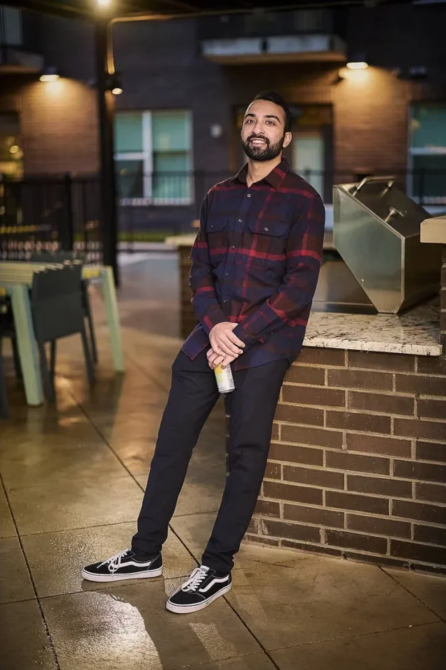 Bearded man in a red and black plaid shirt holding a spray can at night, a full body fashion shot for a dating profile