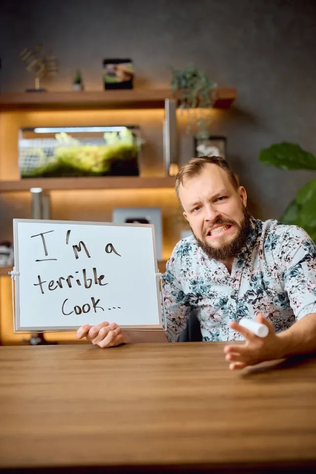 Man holding a humorous whiteboard sign at a warm bar setting, a personality forward Austin dating profile photo