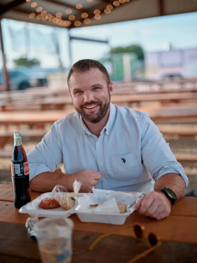 Bearded man smiling at the camera beside an Austin taco truck, used as the hero shot on his dating profile