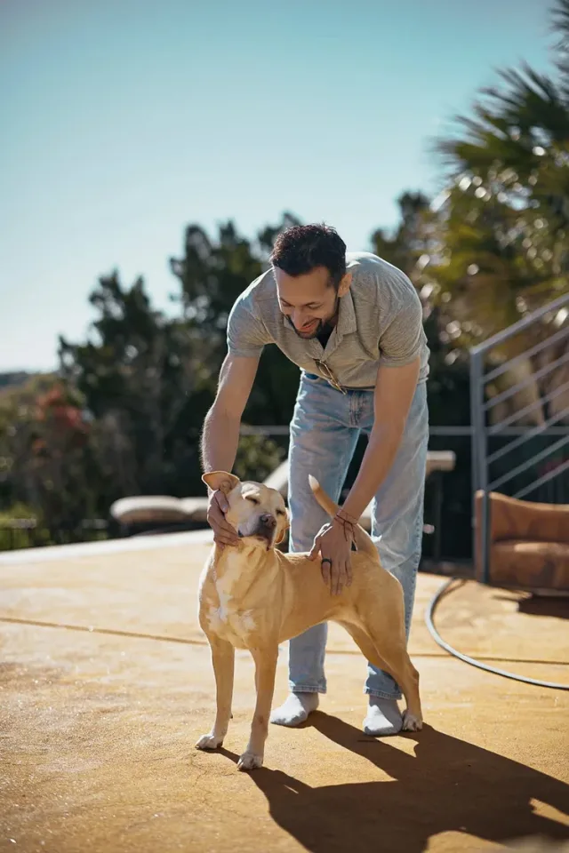 Man smiling with his dog next to a pool, a fun moment from an Austin dating photography session