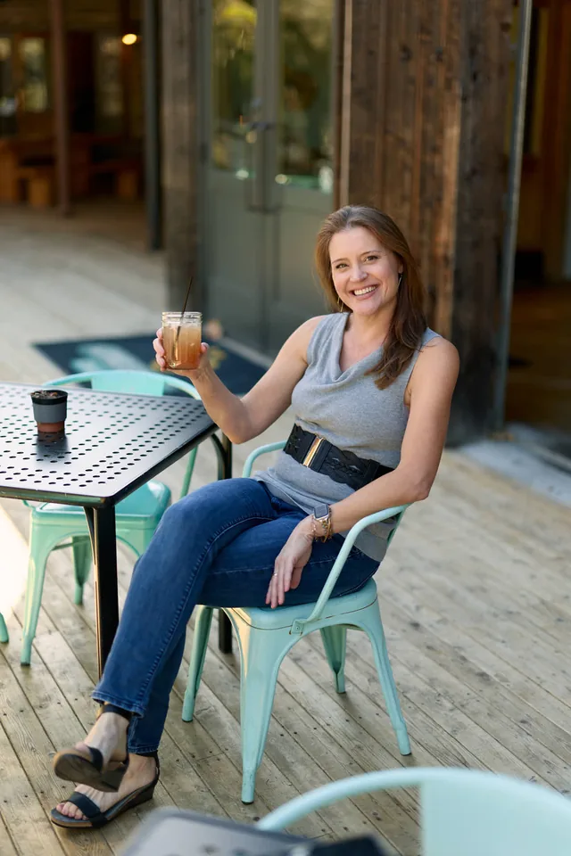 Woman raising a drink at a patio table, a dating profile photo by Eli Samuel