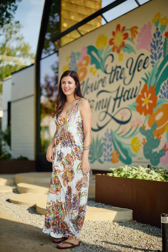 Woman in a floral maxi dress in front of a colorful mural, a full length style shot for a dating profile