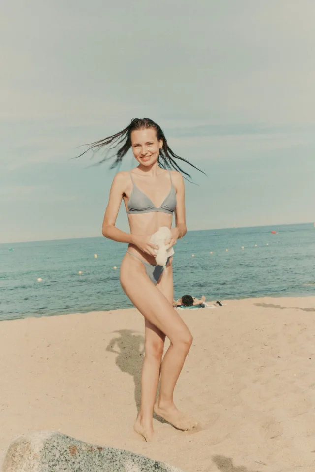 Smiling woman with wet hair flicking back on a sunny beach, a dating profile photo by Eli Samuel