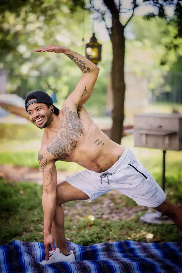 Man doing a yoga pose in front of green foliage, smiling in an Austin online dating profile photo