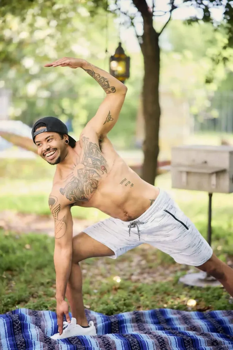 Man doing a yoga pose in front of green foliage for an online dating profile photo