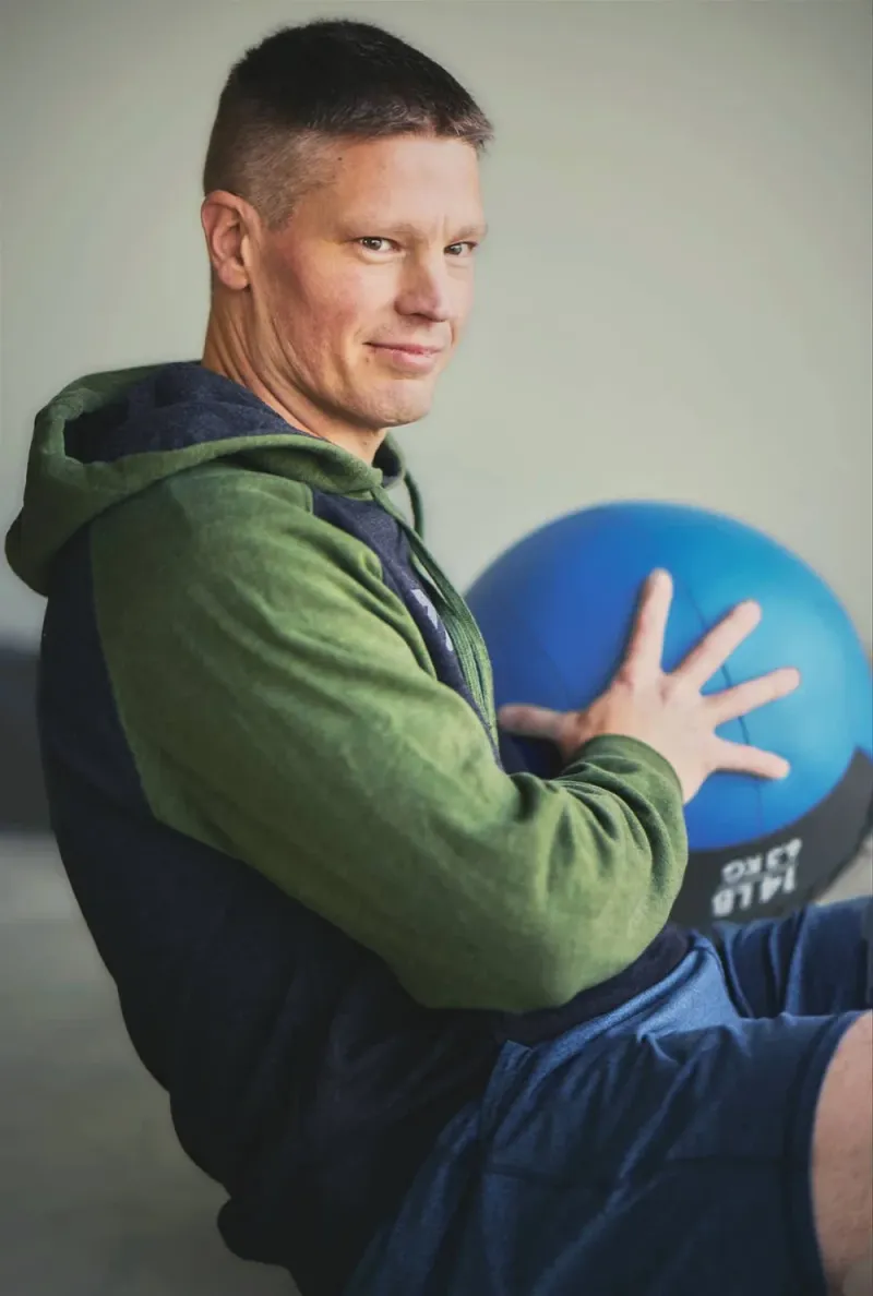 Man training in a garage with a medicine ball, a fitness lifestyle dating profile photo